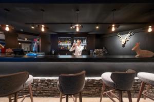 a woman taking a picture of a bar with chairs at Hotel Cristina in Pas de la Casa