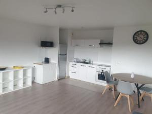 a kitchen with white cabinets and a table and chairs at Appartement idéal JO / Ideal apartment rental for the Olympic Games! in Saint-Denis
