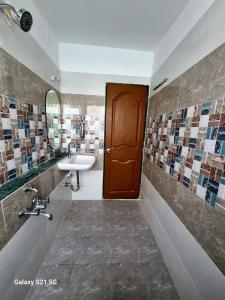 a bathroom with a sink and a brown door at JOY HOSTEL - Digital Nomads Hostel & PG - Koregaon Park in Pune