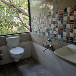 a bathroom with a toilet and a sink and a window at JOY HOSTEL - Digital Nomads Hostel & PG - Koregaon Park in Pune +18 photos