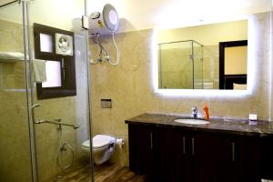 uma casa de banho com um lavatório e um chuveiro com um espelho. em When In Gurgaon - ARTEMIS HOSPITAL 1 Min Walk, FORTIS & MEDANTA 4 Mins Drive em Gurgaon