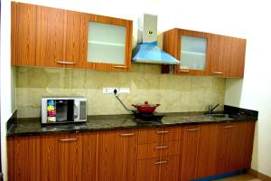 cocina con armarios de madera y microondas en When In Gurgaon - ARTEMIS HOSPITAL 1 Min Walk, FORTIS & MEDANTA 4 Mins Drive, en Gurgaon