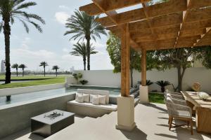 a patio with a pool and a wooden pergola at Elara Villas in Dubai