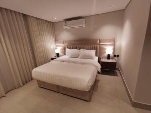a bedroom with a large bed with two lamps on tables at شقة فاخرة بالقرب من البوليفارد A13 in Riyadh