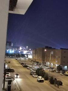 a city street at night with cars parked in a parking lot at شقة فاخرة بالقرب من البوليفارد A13 in Riyadh