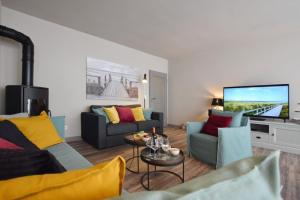 un salon avec deux canapés et une télévision à écran plat dans l'établissement Ferienhaus Barke 17, à Tinnum