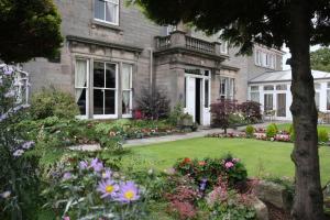 a garden with flowers in front of a house at Sunninghill Hotel in Elgin