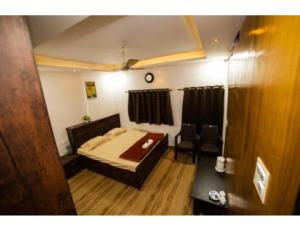1 dormitorio con 1 cama y 1 silla en Bisman Lodge, Jabalpur, en Jabalpur