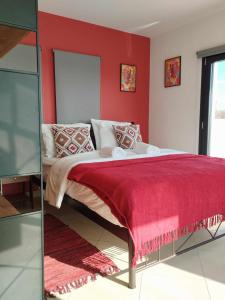 a bedroom with a bed with a red wall at Nest & nook in Chios