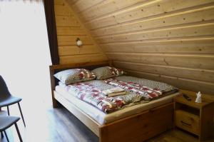 a bed in a room with a wooden wall at Willa Pod Lasem in Biały Dunajec