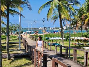 Eine Frau steht auf einer hölzernen Promenade in der Nähe eines Strandes. in der Unterkunft Kitnet Aconchegante em Vitória, B. República in Vitória