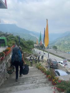 um grupo de pessoas com mochilas a subir uma colina em Green Mountain Homestay Munshyari em Munsyari