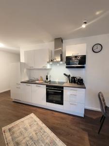 a kitchen with white cabinets and a clock on the wall at Winterberg Appartement 21128 in Winterberg