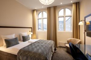 a hotel room with a bed and a desk and windows at Ascot Hotel in Copenhagen