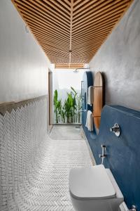 a bathroom with a toilet and a blue wall at Azora by Ayatana, Goa in Morjim