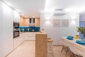 uma cozinha com paredes brancas e uma mesa com cadeiras em Vivendos New y Luxury apartment city center em Torremolinos
