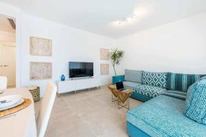 a living room with a blue couch and a tv at Vivendos Lujoso apartamento de playa in Torremolinos