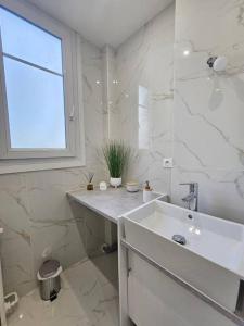 a white bathroom with a sink and a window at Magnifique Appartement Clichy in Clichy
