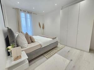 a white bedroom with a bed and a window at Magnifique Appartement Clichy in Clichy