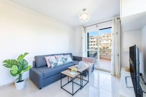 a living room with a blue couch and a tv at Estupendo apartamento junto a magníficas playas in Torremolinos