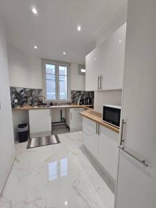 a large kitchen with white cabinets and a window at Magnifique Appartement Clichy in Clichy