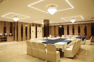 uma sala de conferências com uma mesa longa e cadeiras brancas em Karon Hotels - Lajpat Nagar em Nova Deli