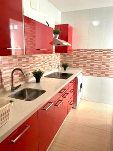 una cocina con armarios rojos y fregadero en Bonito Apartamento en la Macarena en Sevilla