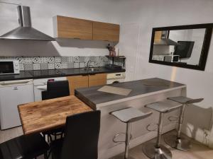 a kitchen with a counter with stools and a table at Gîte pour professionnels en déplacement - CENTRE VILLE - Parking gratuit in Bellac +11 photos