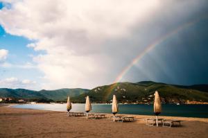 einen Regenbogen über einem Strand mit Stühlen und Sonnenschirmen in der Unterkunft Appartamenti Rosa Campo Mare - Goelba in Marina di Campo