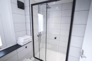a glass shower in a bathroom with white tiles at Camden Serviced Apartments by Globe Apartments in London