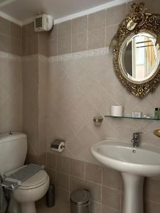 ein Badezimmer mit einem WC, einem Waschbecken und einem Spiegel in der Unterkunft monte kristo in Ermoupoli