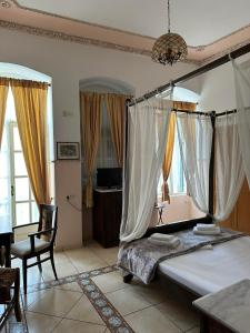 um quarto com uma cama, uma cadeira e janelas em monte kristo em Ermoupoli