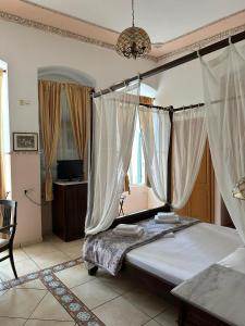 een slaapkamer met een bed met gordijnen en een kroonluchter bij monte kristo in Ermoupoli