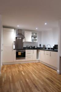 uma cozinha com armários brancos e piso em madeira em ***Spotless, Bright 1 Double Bed Apartment*** em Bath