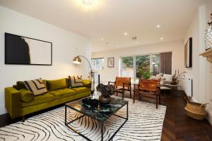 a living room with a yellow couch and a table at The Redbridge Sanctuary - Spacious 3BDR House with Garden in London