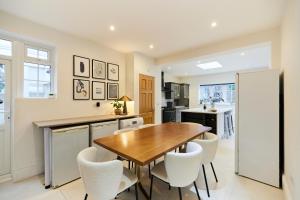 a kitchen with a wooden table and white chairs at The Redbridge Sanctuary - Spacious 3BDR House with Garden in London