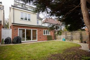 a house with a lawn in front of it at The Redbridge Sanctuary - Spacious 3BDR House with Garden in London