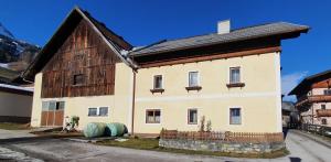 ein Haus mit zwei blauen Fässern davor in der Unterkunft Neufangbauer, Familie Sabine und Peter Hauser in Dorfgastein