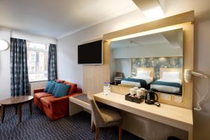 a hotel room with a bed and a desk with a mirror at Bedford Hotel in London