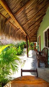 a patio with benches and a thatched roof at Las Palmas in Bacalar