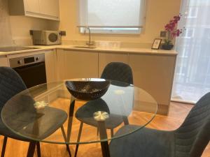 uma cozinha com uma mesa de vidro e cadeiras numa cozinha em New 2 Bedroom Apartment Rickmansworth Town Centre em Rickmansworth