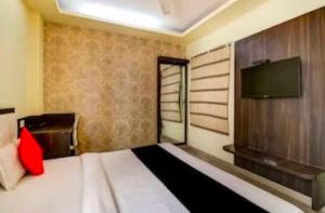 a bedroom with a large bed with a tv on the wall at Collection O Hotel Kashi Inn in Varanasi