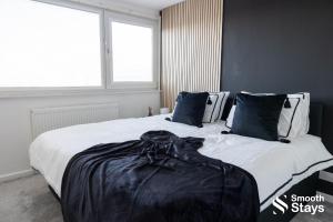 1 dormitorio con 2 camas con sábanas y almohadas negras en Modern 2 Bed House With Driveway en Longton