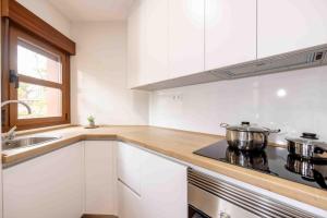 a kitchen with white cabinets and a stove and a sink at Apartamentos turísticos Plaza Sevillano , by CartagenaSpain in Cartagena