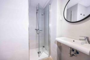 La salle de bains est pourvue d'une douche, d'un lavabo et d'un miroir. dans l'établissement Apartamentos turísticos Plaza Sevillano, à Carthagène