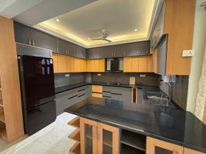 a kitchen with a black refrigerator and wooden cabinets at 4 BHK Mountain View Villa In Rishikesh in Rishīkesh