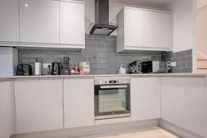 a white kitchen with white cabinets and appliances at Luxury 2 Bed Split Level Maisonette W/Parking in London