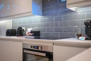 a kitchen with blue tiles on the wall at Luxury 2 Bed Split Level Maisonette W/Parking in London