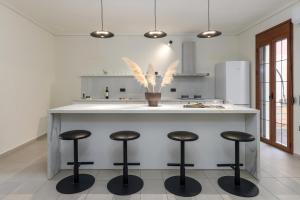 Una cocina con una encimera con cuatro taburetes de bar. en Centro Y Mar I, en Argostoli