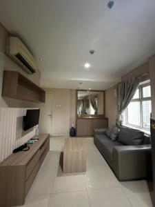 een woonkamer met een bank en een tv bij Madison Park Apartment Near Mall Central Park in Jakarta